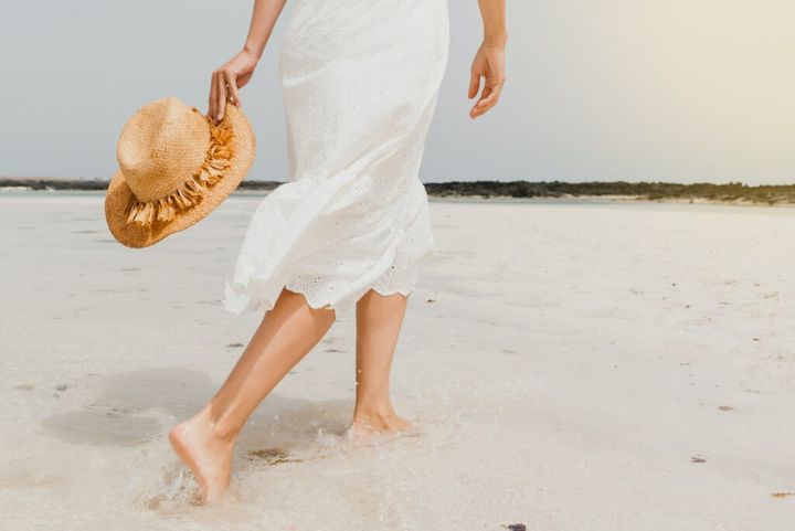 Woman in dress walking on sandy beach