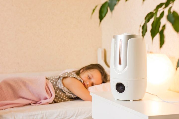 Cute little girl sleeping in bedroom with air humidifier.