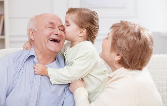 Wnuczka całuje dziadka, razem świętują dzień dziadka i dzień