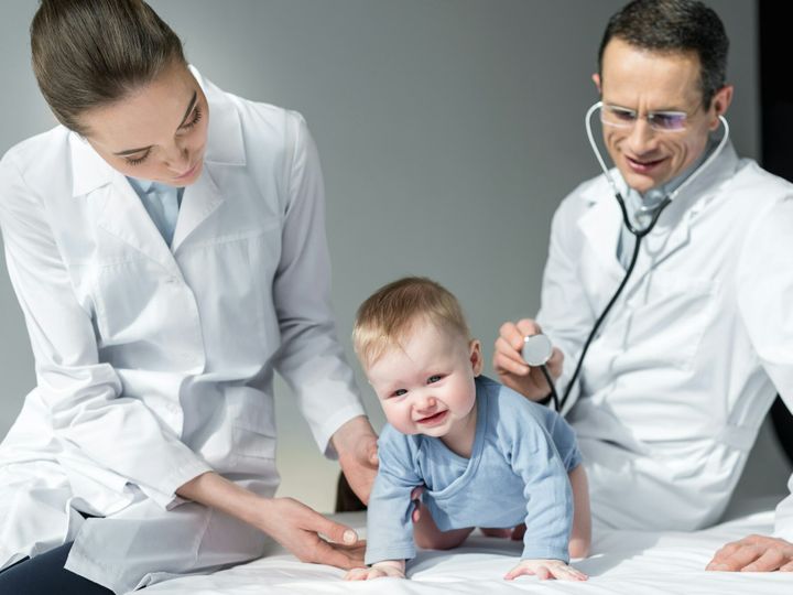 pediatricians trying to check breath of sad baby