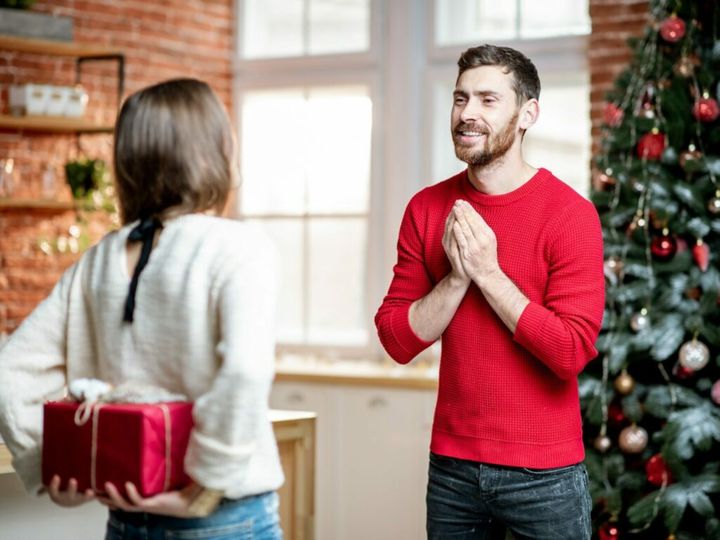 Woman giving a New Year gift for a man at home