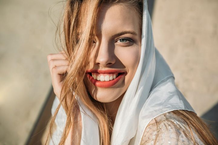 beautiful smiling girl in white silk scarf looking at camera