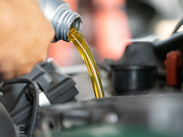 Pouring engine oil to car engine. Fresh oil poured during an oil change to a car.