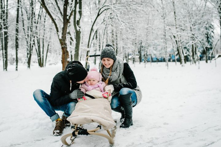 Mom, dad kissing daughter stand outdoors on the background winter. Happy family walks in the park