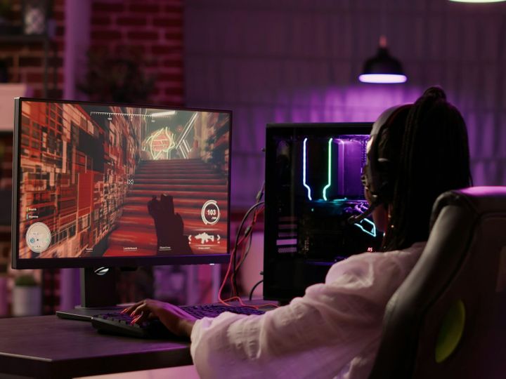 Over shoulder view of african american gamer girl playing online games using gaming pc setup