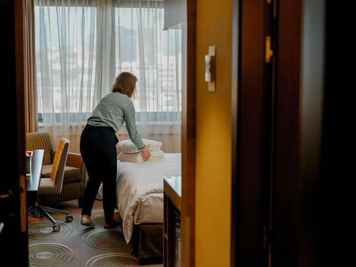 A housekeeper in a uniform makes a bed preparing luxury hotel room for guests cleaning and travel