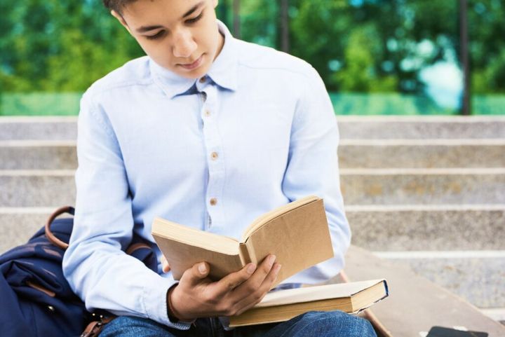 Teenage Boy Reading Books Outdoors