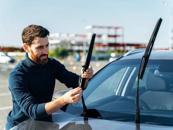 Male auto owner checking windshield wiper at the street