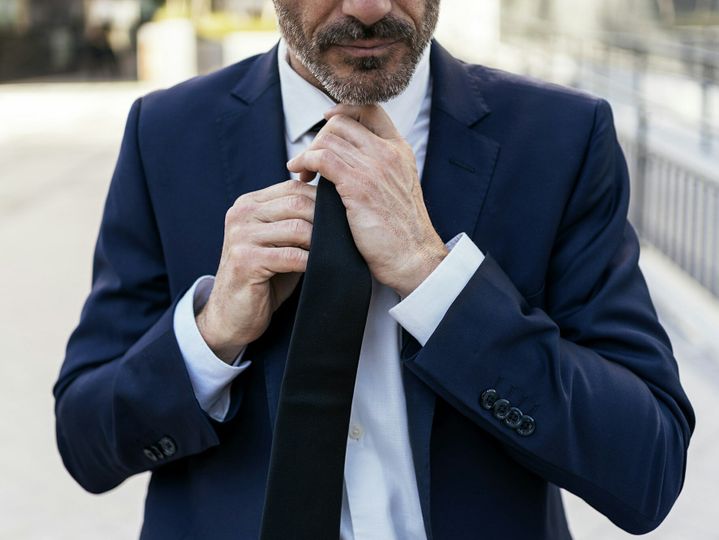 Crop businessman in suit adjusting tie