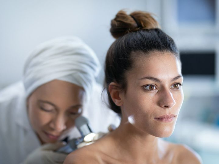 Female doctor checking patient with dermatoscopy in clinic