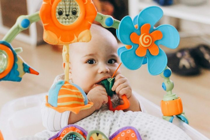 Cute chubby baby playing with colorful toys. Baby chewing toy. First teeth growing out