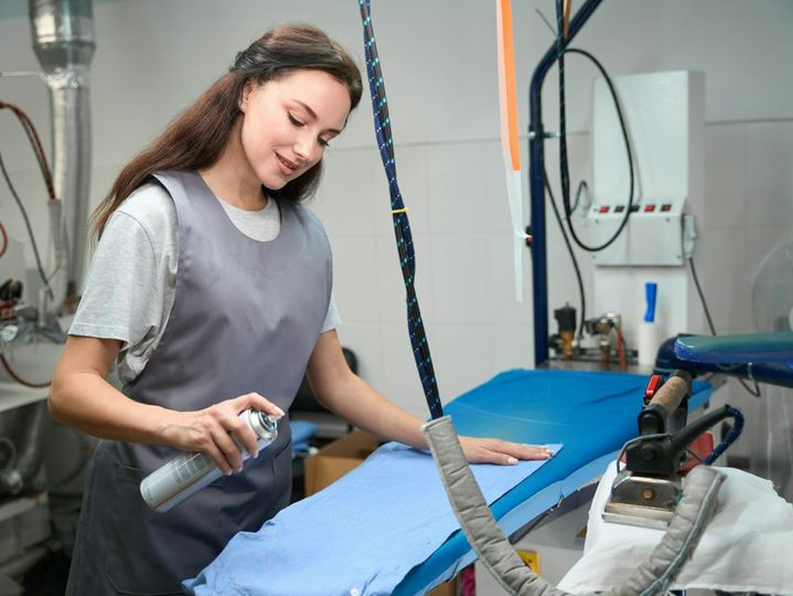 Washing house worker spraying special liquid at garment before ironing