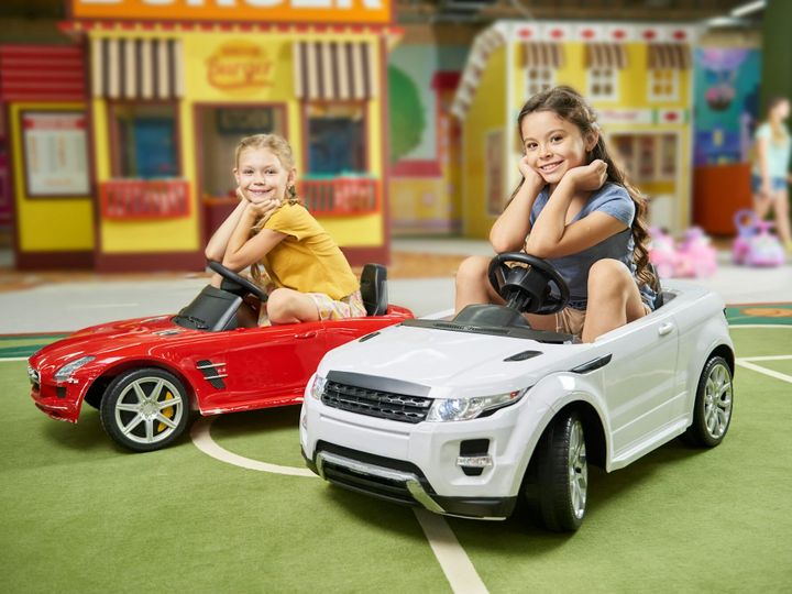 Happy kids sitting in electric toy cars.