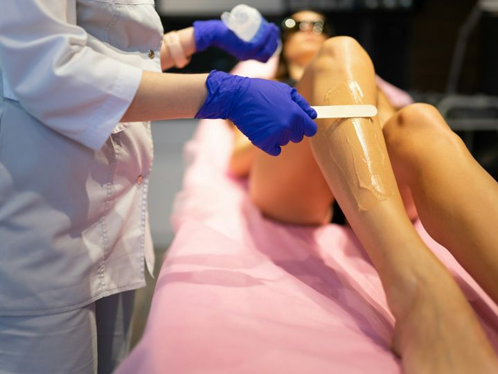 Beautician applies laser depilation gel to the patient's legs