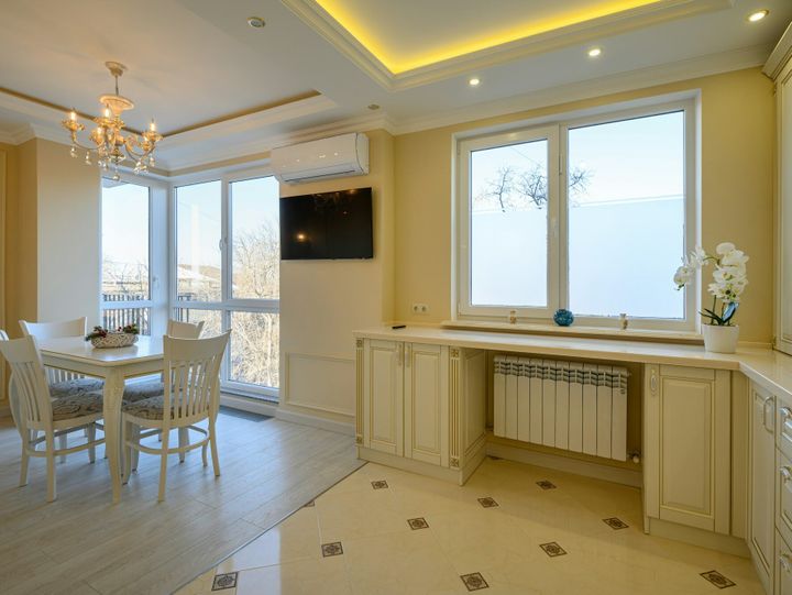 Classic white and beige large kitchen with dining table in studio apartment