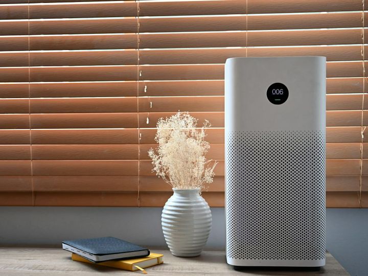 Air purifier in front of windows in living room for fresh air and healthy life.