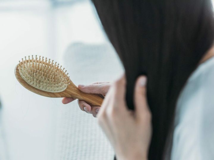 cropped shot of young brunette woman holding hairbrush, hair loss concept