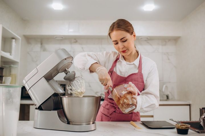 selective focus on modern kitchen machine and wooden cutting board on table in kitchen.