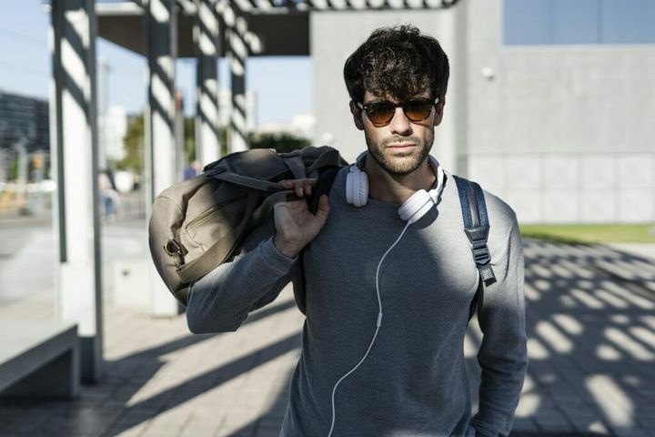 Cool man holding travelling bag in the city