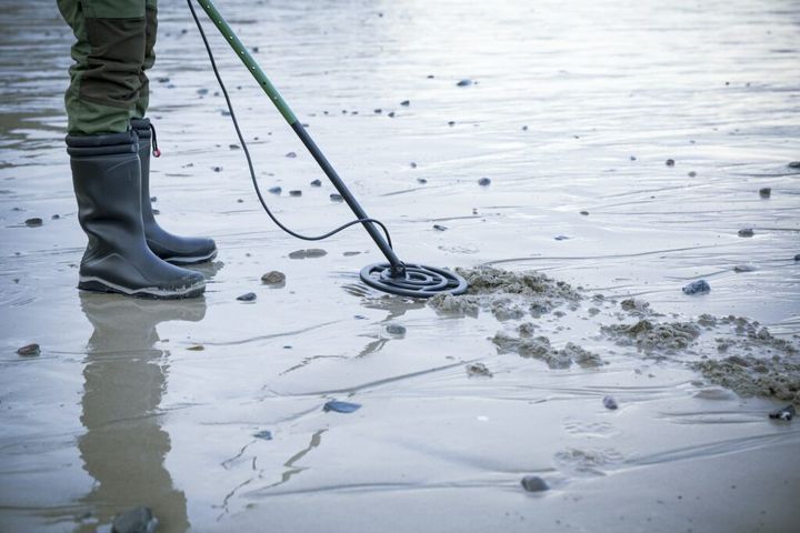 Man with metal detector at the sand beach