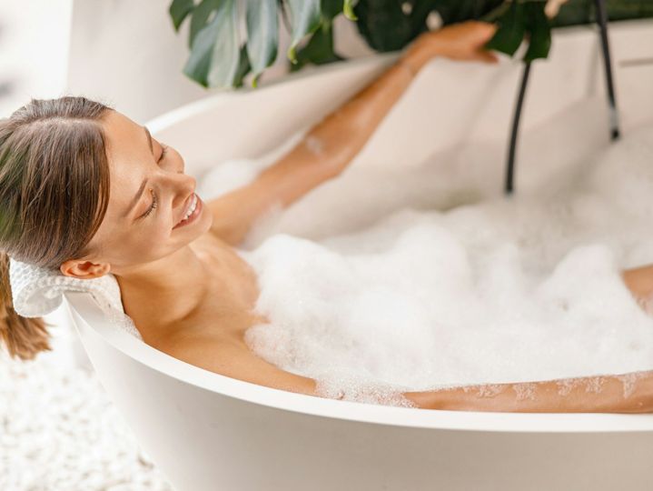 Lovely young woman enjoying bath foam while relaxing in the bathtub at home