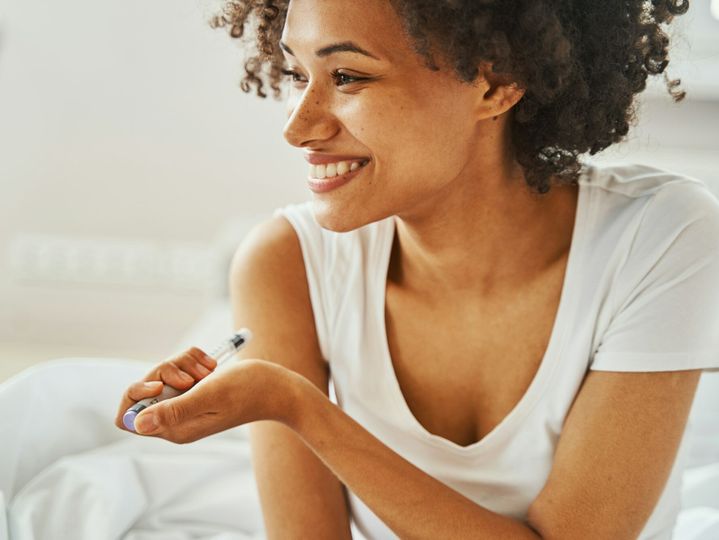 Smiling female diabetic giving herself an injection