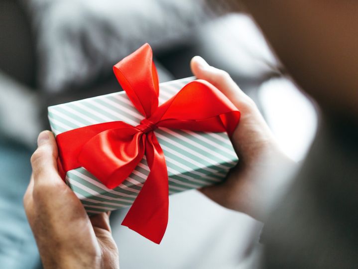 Man holding gift with red ribbon