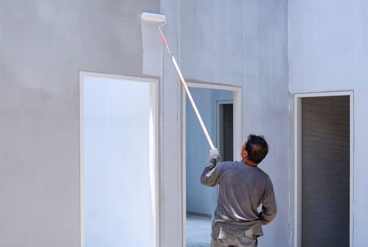 Asian construction worker painting white primer color on concrete wall in house construction site