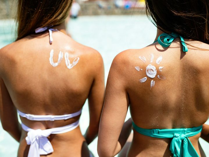 Attractive woman with healthy skin applying sunscreen for healthy tanning