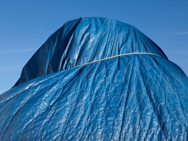 Low angle view of a blue tarpaulin, tied around a heap.
