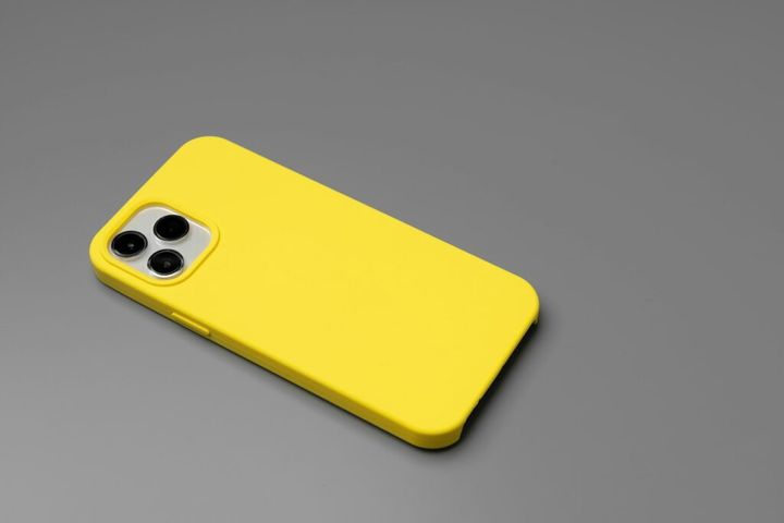 Modern smartphone in yellow case on gray background