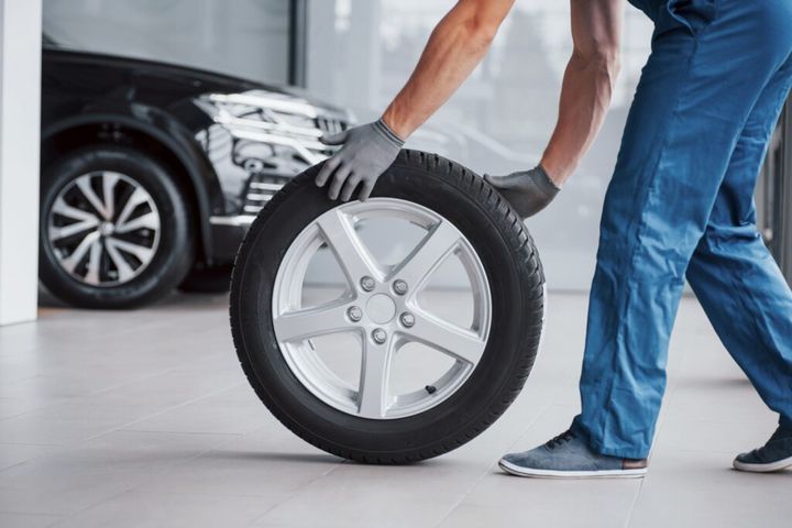 Mechanic holding a tire tire at the repair garage. replacement of winter and summer tires