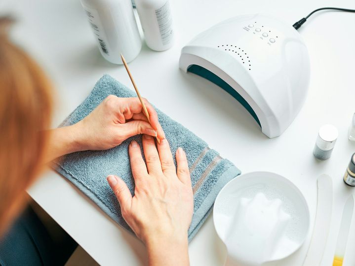 Woman preparing nails to apply gel hybrid polish using UV lamp. Beauty wellness spa treatment