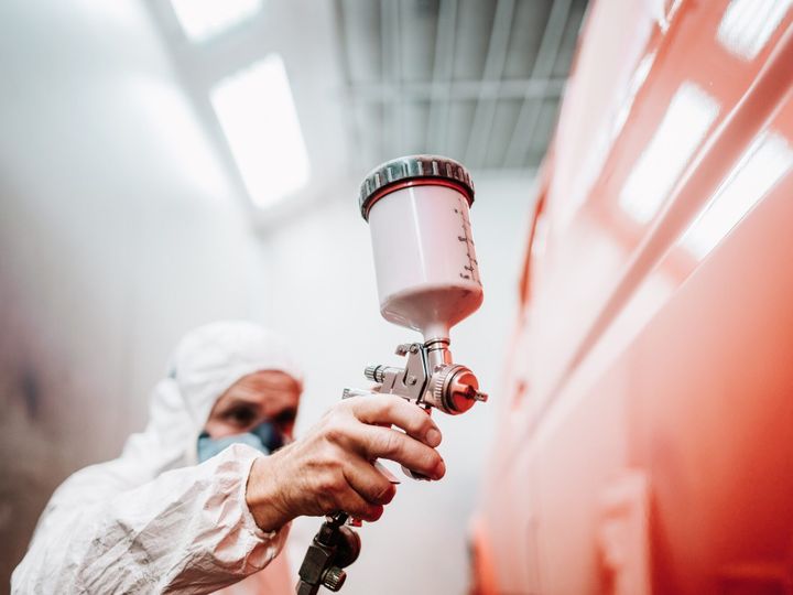 close up of paint spray gun, worker painting a car