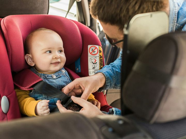 Father fasten his baby in car seat