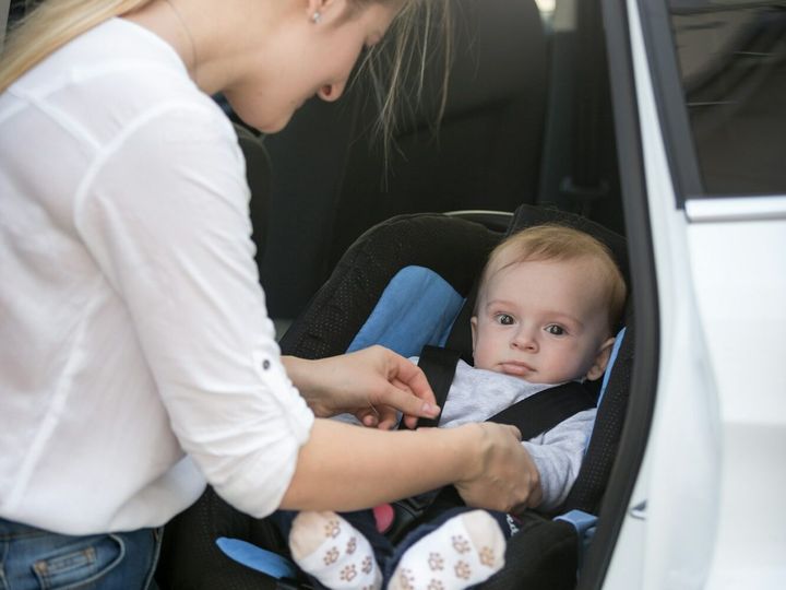 Mother seating her baby in car safety seat