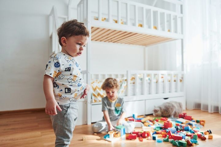 Two little boys have fun indoors in the bedroom with plastic construction set