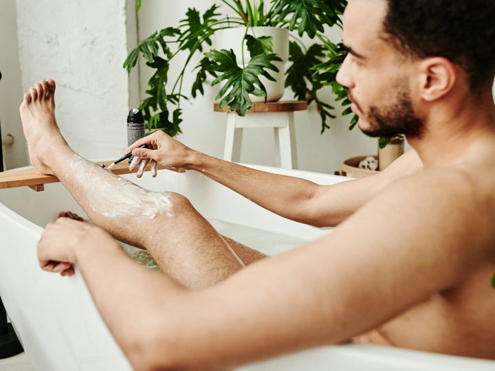 Guy shaving his legs in bath