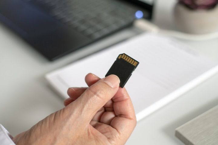 Man holding an SD card to insert in a laptop.