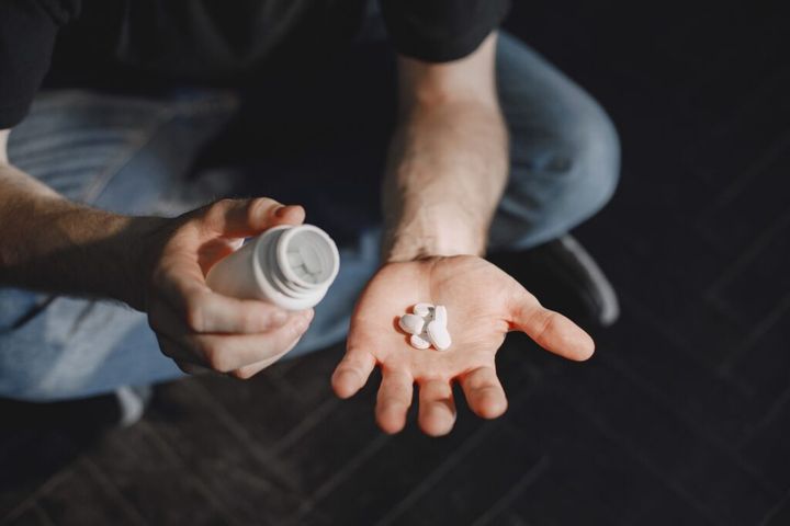 Man with pills sitting on the floor