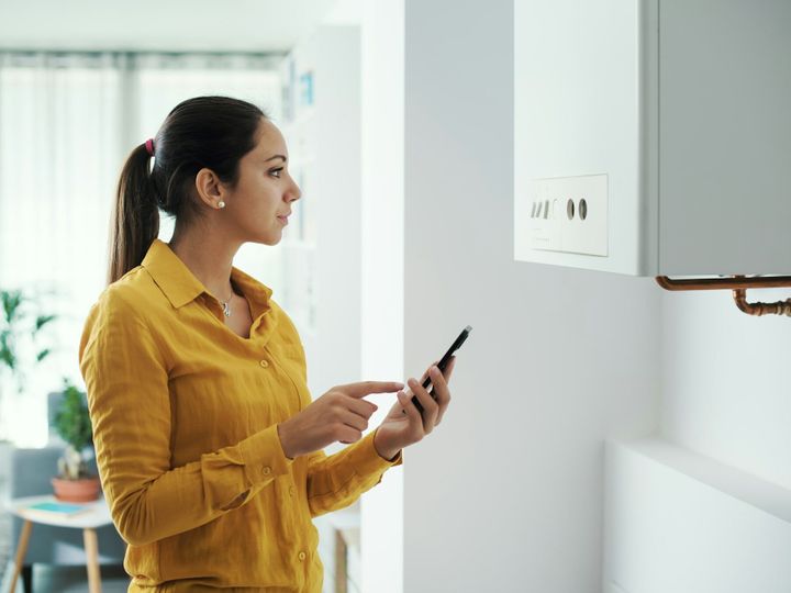 Woman managing her smart boiler using her phone