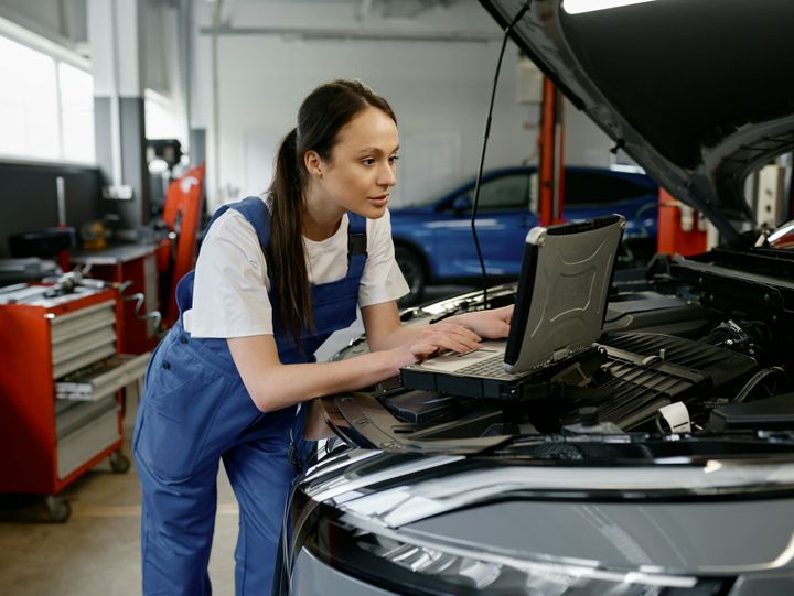 Young woman car engineer providing computer diagnostics