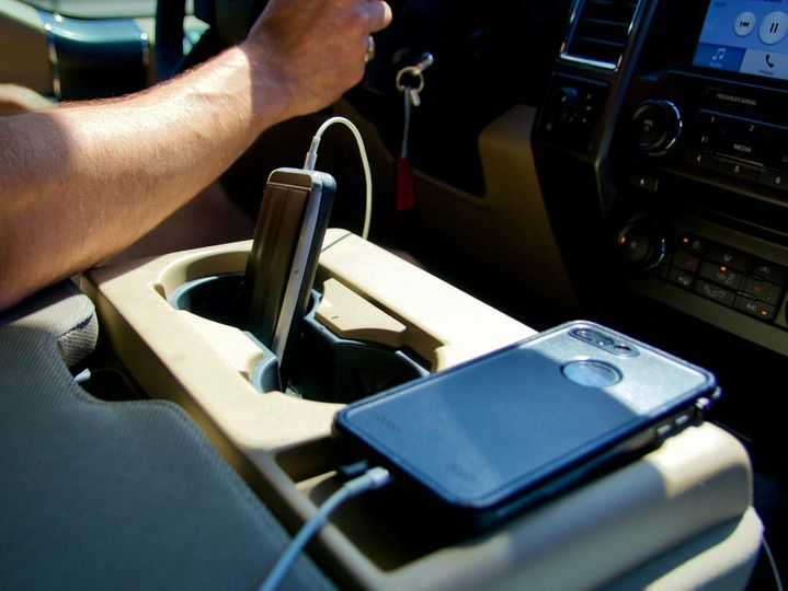 Man driving car on road trip with two phones charging