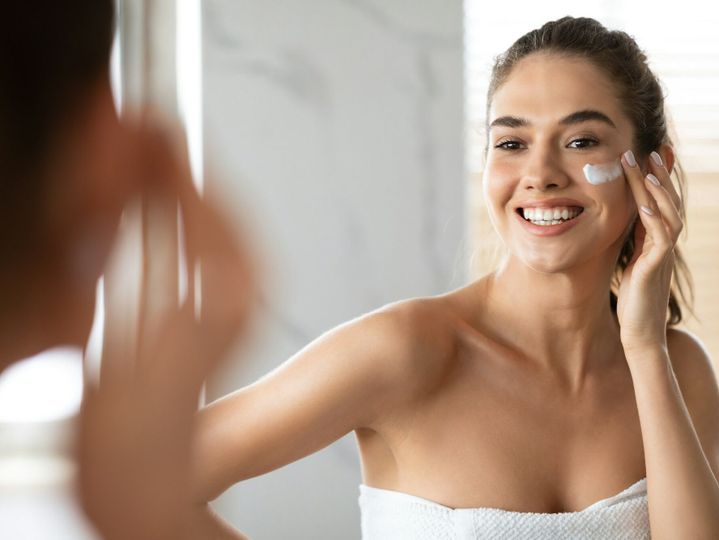 Woman Applying Cream Under Eyes Moisturizing Skin Posing In Bathroom
