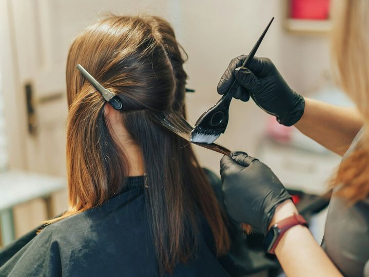hair stylist dyes hair with a brush with foil