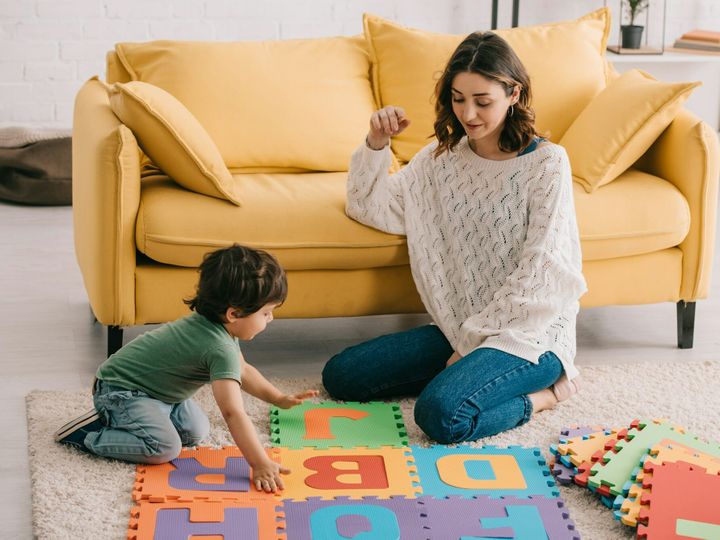 Mother and son playing with alphabet puzzle mat on carpet