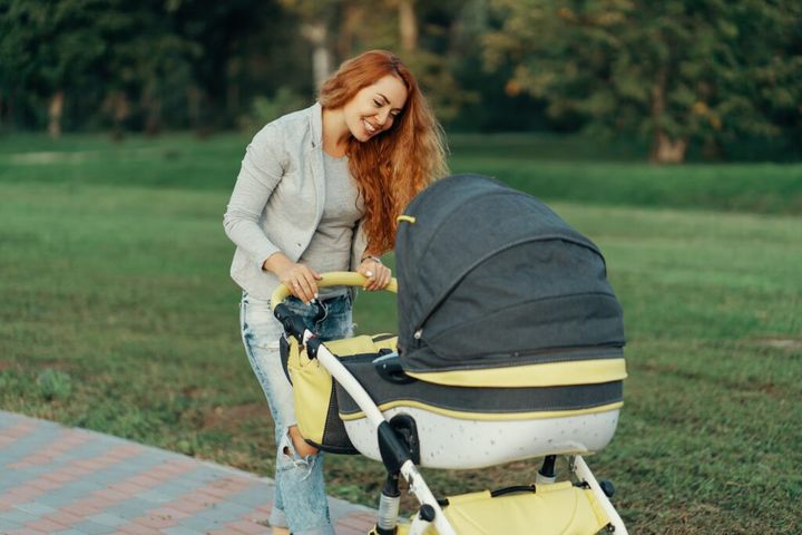 Mother enjoying walk carrying her little child in his baby troll