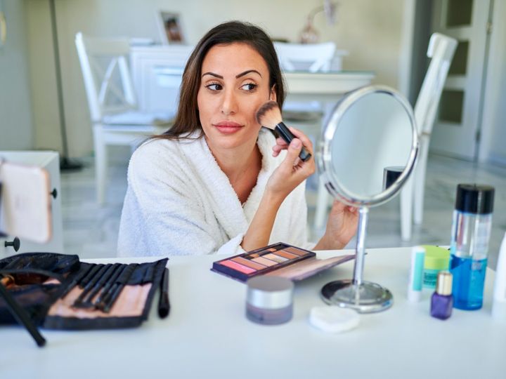 Woman putting on makeup in front of the mirror