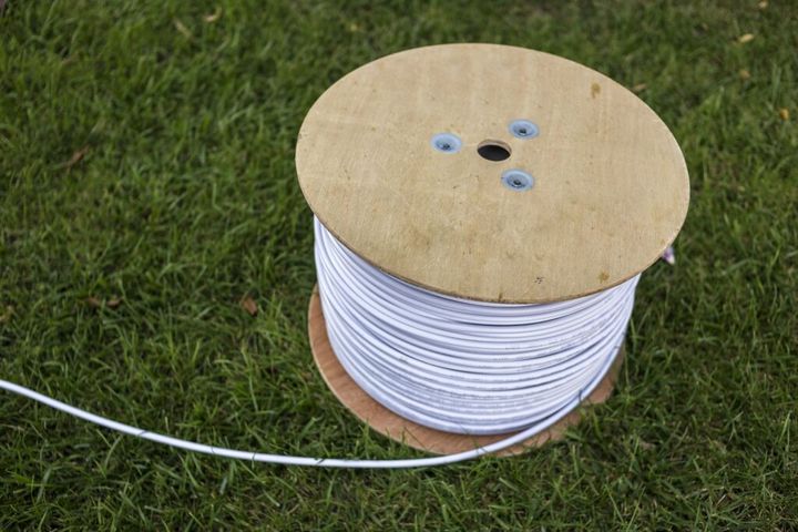 Top view of roll of white industrial electrical cable on large wooden reel