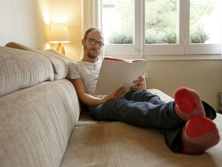 Man relaxing on sofa, reading book